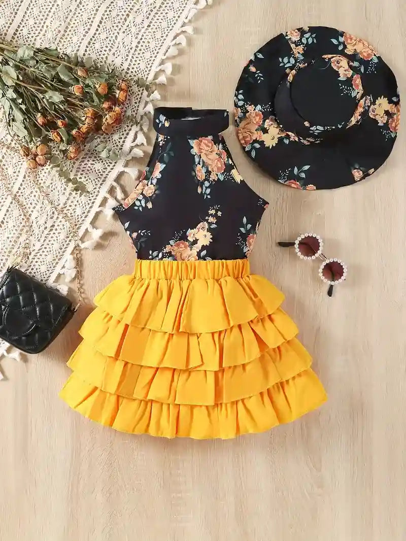 Floral top and yellow skirt set with a black hat and black bag on a textured surface.