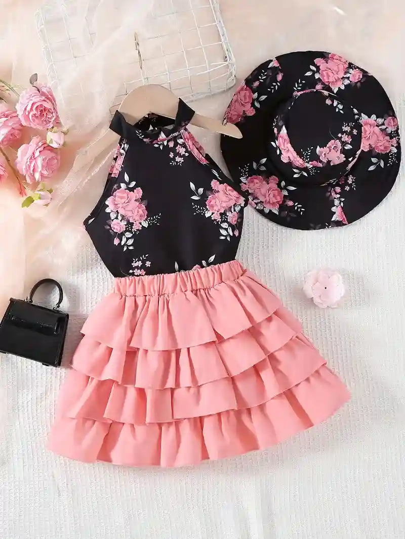 Black floral top and pink ruffled skirt with matching hat on a light background